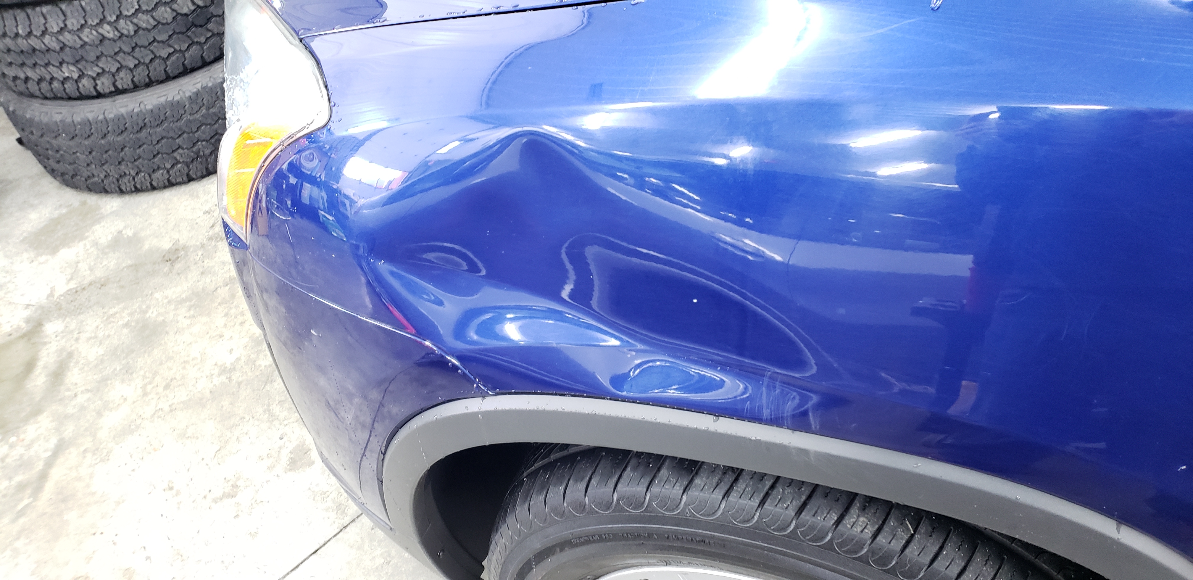 Blue vehicle fender before paintless dent repair